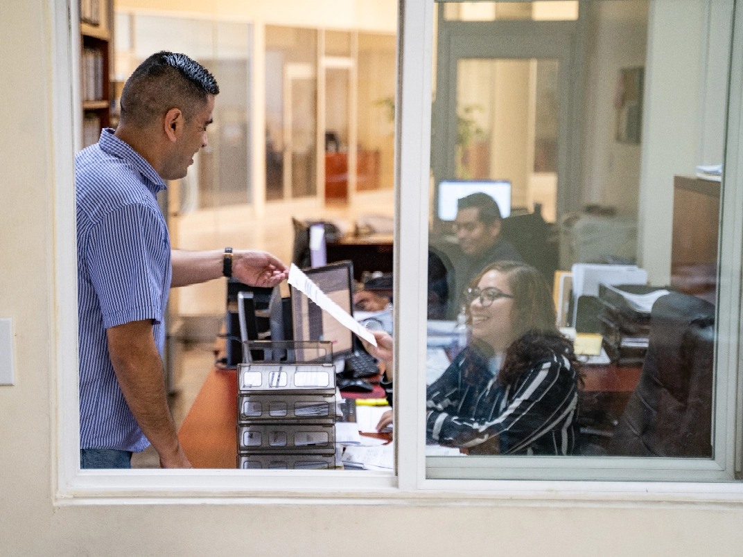 A man and woman standing in front of a window in an office.